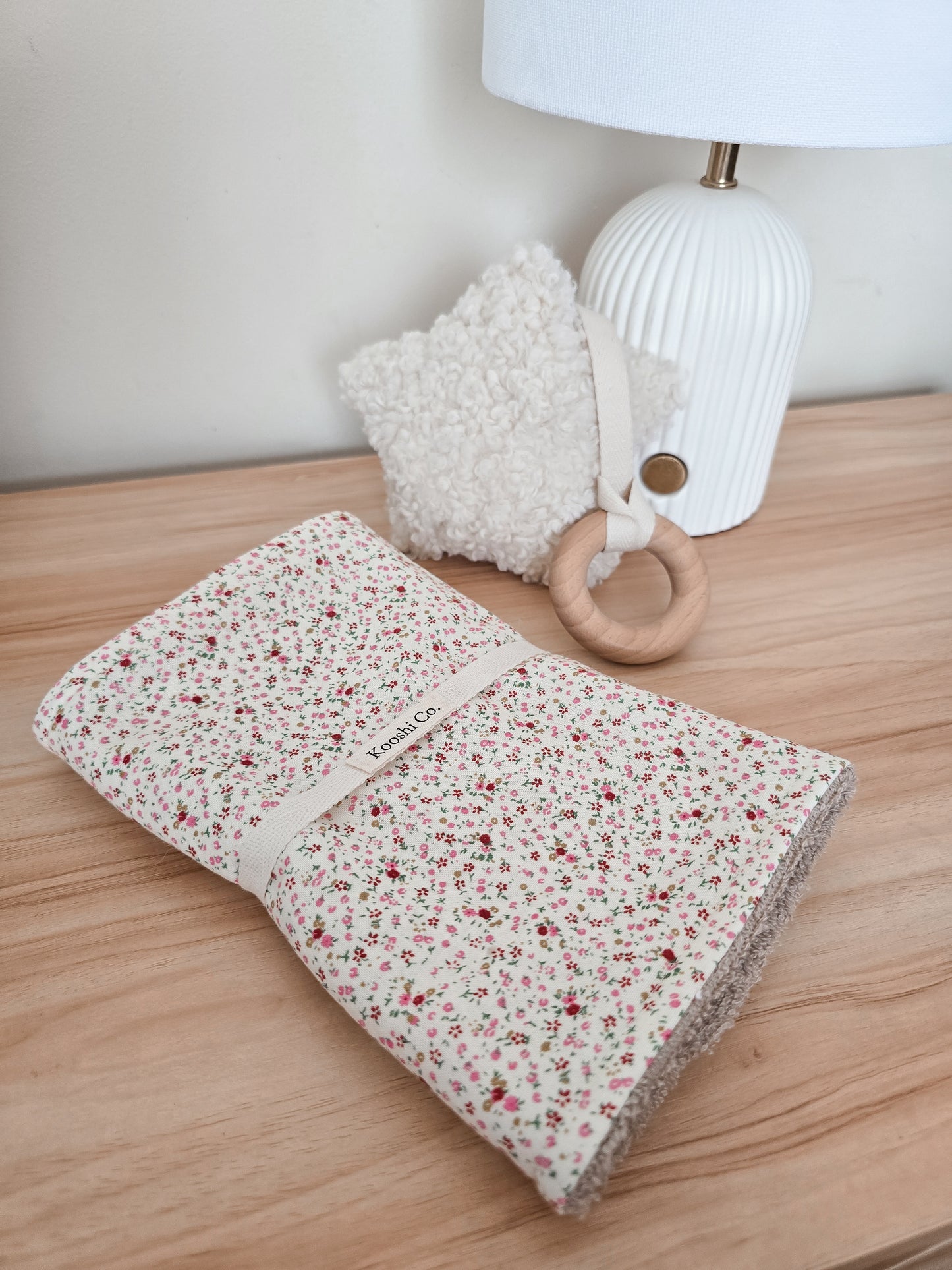 Single burp cloth featured with ditsy floral print with star plush charm attached to teething ring.
