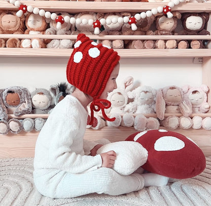 Happy little girl with mushroom cushion in playroom. Bright red, classic colour. 