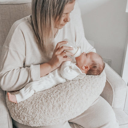 Cosy Mum feeding her baby in nursing chair with our Moon Support Cushion (for bottle feeding or breastfeeding).