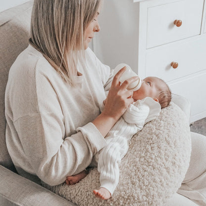 Cosy Mum feeding her baby in nursing chair with our Moon Support Cushion (for bottle feeding or breastfeeding).