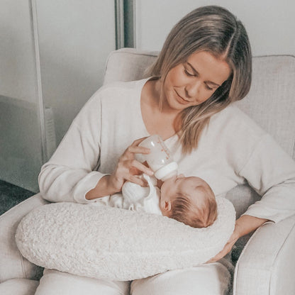 Cosy Mum feeding her baby in nursing chair with our Moon Support Cushion (for bottle feeding or breastfeeding).