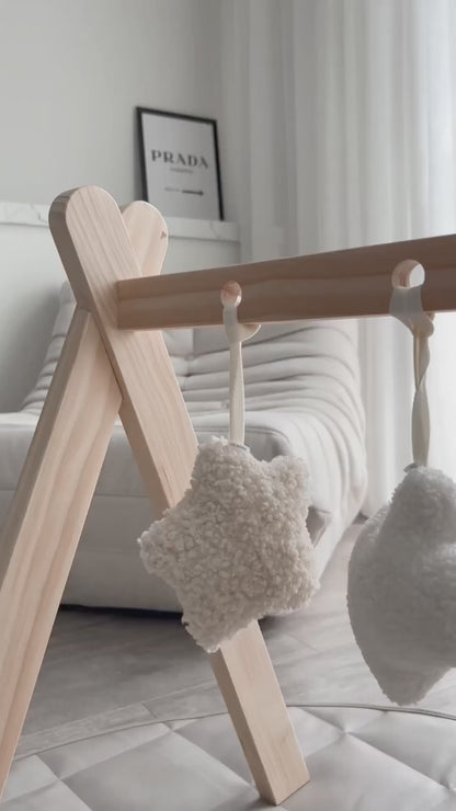 Video of plush charm set on play gym frame in aesthetic nursery. Neutral colours in stars, clouds and moons. 